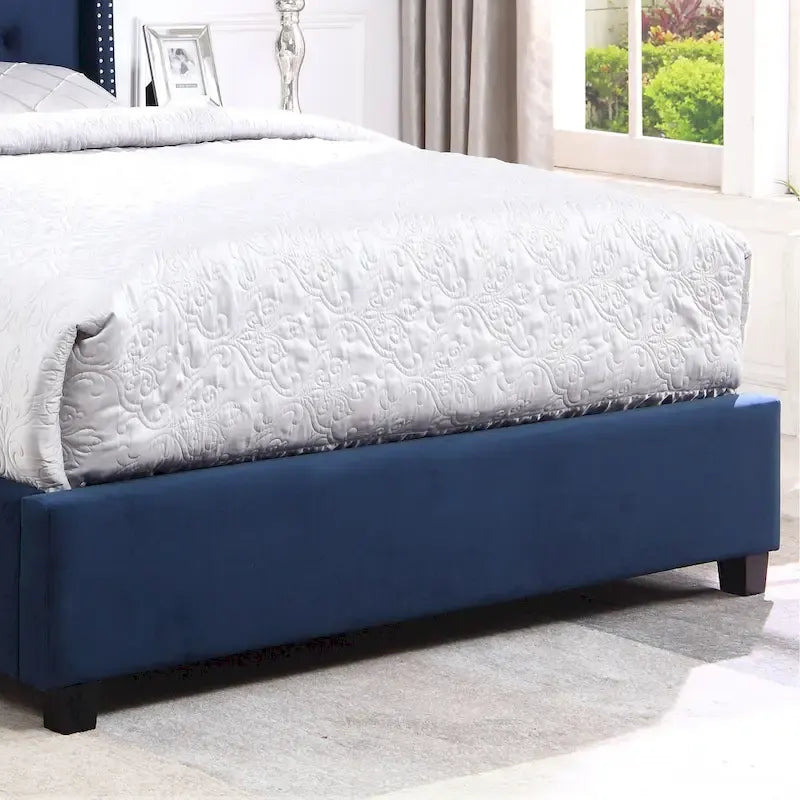 Cama tapizada con cabecera de orejas y ribete de tachuelas